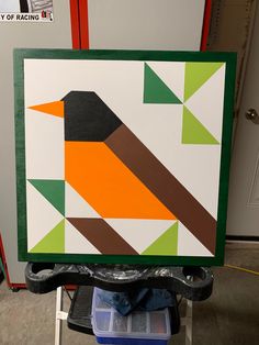 a colorful bird is sitting on top of a piece of art that is being worked on