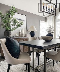 a dining room table with chairs and a vase on it's centerpiece in front of a mirror