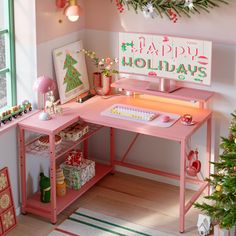 a pink desk topped with a computer next to a christmas tree