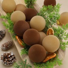 an arrangement of different types of food on a wooden tray with pine cones and oranges