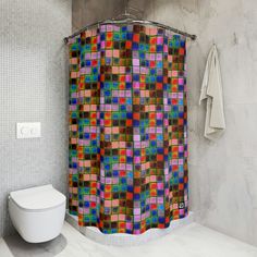 a colorful shower curtain in a bathroom next to a white toilet and wall mounted faucet