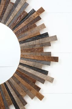 a circular mirror made out of wooden planks on a white wall with wood strips in the middle