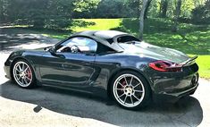 a black sports car is parked on the side of the road in front of some trees