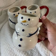 three snowman mugs sitting next to each other on a white towel with red handles