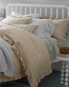 a white bed topped with lots of pillows and blankets