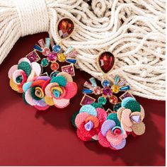 Casting Jeweled Earring With Fabric Flower Charm/ Statement Earrings Weight: 0.07 Lb. Dimensions: (L X W) 3.25 X 2.5 In. Style #901199050 Spring Party Earrings With 3d Flowers, Summer Party 3d Flower Earrings, Flower Charm Earrings For Party, Flower Drop Earrings For Party, Party Flower Drop Earrings, Flower Charm Drop Earrings For Party, Red Flower Charm Jewelry For Spring, Red Jewelry With Flower Charm For Spring, Red Spring Jewelry With Flower Charm