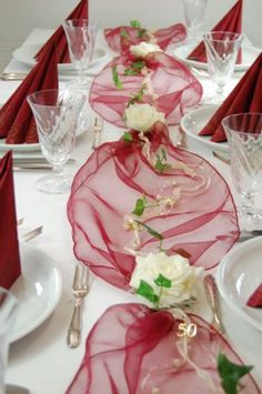 the table is set with red and white plates, silverware, and napkins