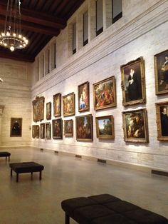 an art gallery with many paintings on the wall and benches in front of one another