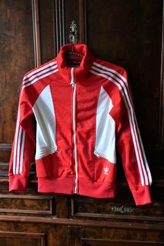 Beautiful Vintage Adidas track jacket from the 1980s. Slightly shiny red fabric with white inserts on the sides and on the back. Raglan sleeves, YKK front zipper, two zipped front pockets. Embroidered Adidas Trefoil on the left waist. Elasticated cuffs and waistband. Iconic stripes along the sleeves. Fleeced inside. Made in France! Amazing 80s Vintage piece - combine casual with sneakers, jeans or track pants! ERA: 1980s BRAND: Adidas COLOR: Red, white FABRIC: 54% polyester, 46% triacetate SIZE: Luxury Track Jacket For Sports, Red Sporty Track Jacket With Three Stripes, 90s Red Track Jacket For Sports, 90s Style Red Track Jacket For Sports, Retro White Track Jacket For Sports, Red Track Jacket With Three Stripes, Sporty Red Outerwear With Three Stripes, Red 90s Style Track Jacket For Fall, 90s Red Fall Track Jacket