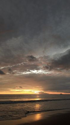 the sun is setting over the ocean with clouds in the sky and water on the beach