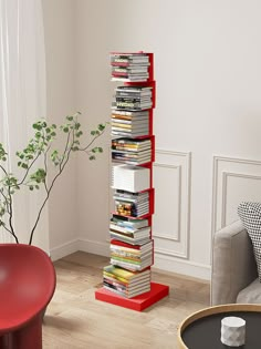 a stack of books sitting on top of a red book shelf next to a couch