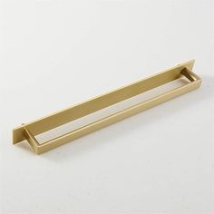 a brass drawer pull on a white surface with an angled bar in the center and bottom