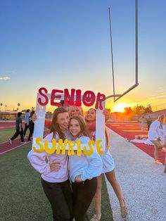 two girls holding up a sign that says senior sunrise on the side of a field