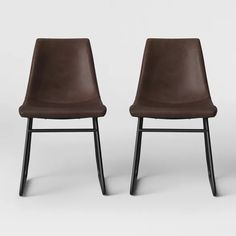 two brown leather chairs sitting side by side on a white background, one is black and the other has dark wood legs