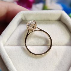 a gold ring with a diamond in it sitting inside a white box on a table