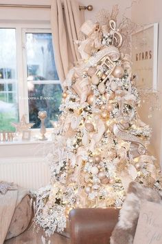 a white christmas tree decorated with gold ornaments