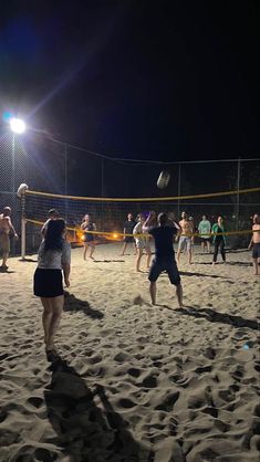 people playing volleyball on the beach at night