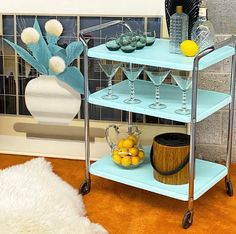 a three tiered serving cart with wine glasses and lemons on the bottom shelf