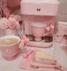 there is a pink coffee maker and cups on the table