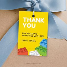 a thank you tag attached to a gift bag with blue ribbon and legos on it