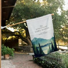 a banner hanging from the side of a building on a clothes line with trees in the background