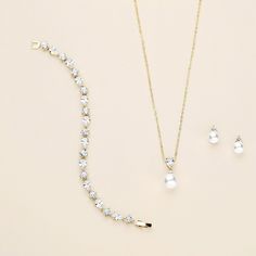 This beautiful gold wedding jewelry set will surely add elegance and beauty on your special day! This necklace and earrings set features sparkling cubic zirconia with bold, light ivory glass pearls. Earrings feature an 8mm glass pearls with three tiny cubic zirconia accent stones. This set is perfect for the bride, bridesmaid, or any occasion and can be worn long after the big day!  DETAILS * High quality cubic zirconia.  * Earrings measure 1/2 inch long and feature an 8mm pearl size. (clip ons Elegant White Jewelry Sets For Brides, Gold Bridal Necklace With Brilliant Cut Crystals, Elegant Cubic Zirconia Bridal Sets For Anniversary, Elegant Bridal Sets With Diamond Accents, Elegant White Bridal Set, Classic Cubic Zirconia Jewelry Sets For Wedding, Classic Wedding Jewelry Sets With Cubic Zirconia, Classic Wedding Jewelry Sets With Sparkling Stones, Elegant Cubic Zirconia Bridal Necklace For Bridesmaid