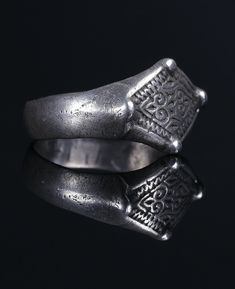 1000-1300s  Silver, Patina Size: 18,75mm,  EU 58-3/8 Overall: 21,92mm Bezel: 16,71 x 12,06mm Ring height: 21,67mm Weight: 3,8g Condition: very fine / wearable A wearable silver ring with a round-section hoop and rhombus-shaped bezel with two pairs of raised bosses is decorated with beautiful floral ornaments and linear incisions on the border. This early islamic rhombus-shaped signet ring is an amazing addition to your antique collection! Feel free to ask any questions and for high resolution pi Medieval Engraved Jewelry For Weddings, Medieval Engraved Jewelry For Anniversary, Medieval Style Engraved Wedding Jewelry, Medieval Engraved Wedding Jewelry, Medieval Sterling Silver Engraved Rings, Traditional Hand Forged Rings As Gift, Medieval Engraved Sterling Silver Rings, Ceremonial Hand Forged Ring Jewelry, Traditional Etched Ceremonial Rings