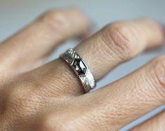 a close up of a person's hand wearing a silver ring with an arrow on it