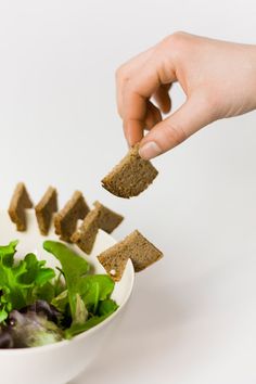 a person is dipping some bread into a bowl of green lettuce and salad