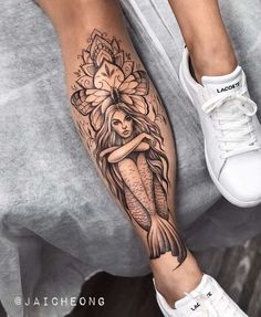 a woman's leg with a tattoo on it and a mermaid holding a flower