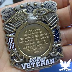 a close up of a person's hand holding a small metal badge with an eagle on it