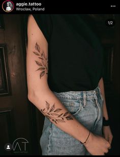 a woman's arm with leaves tattooed on the left side of her arm, in front of a door