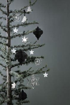 a christmas tree with ornaments hanging from it's branches in front of a gray wall