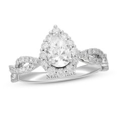 a white gold ring with a pear shaped diamond center surrounded by round brilliant cut diamonds