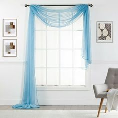 a chair sitting in front of a window with blue sheer curtains hanging on the wall