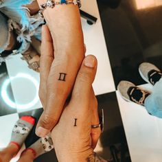 two people holding hands with tattoos on their fingers and one has the letter i tattooed