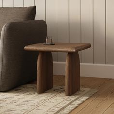 a small wooden table sitting on top of a rug next to a couch in a living room