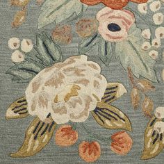 an area rug with flowers and leaves on blue groundcloth, close - up view