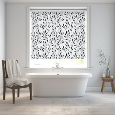 a white bath tub sitting under a window next to a chair