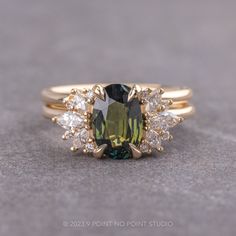 a green and white ring sitting on top of a gray surface with two diamonds around it