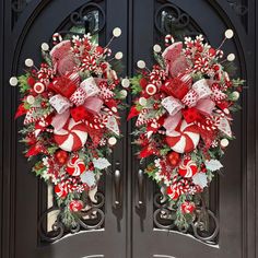 two red and white christmas wreaths on the front doors of a church with candy canes