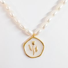 Indulge in the beauty of the Tulip Coin Pendant Pearl Necklace, a meticulously handcrafted piece featuring an enamel tulip flower delicately placed on thick gold-plated brass. The intricate detailing of the enamel work brings the tulip to life, while the lustrous seed pearl necklace adds a touch of elegance and sophistication. This necklace is a perfect fusion of artistry and quality, showcasing the beauty of nature and craftsmanship in a timeless piece that will be treasured for years to come. MATERIALS: Metal: Gold-plated Brass Pendant: Handmade Enamel Pearls: Natural Freshwater Pearl DIMENSIONS Natural stone & Pearl sizes may vary slightly. Necklace Length: 14.2 inches + 4.3 inches extension Pendant Length: 0.9 inches Width: 0.8 inches PROCESSING & SHIPPING All of my pieces are shipped Handmade Gold Enamel Necklaces, Flower Shaped Pearl Charm Necklace Gift, Flower Shaped Pearl Charm Necklace As Gift, Gold Flower-shaped Enamel Jewelry, Flower Shaped Pearl Charm Necklace For Gift, Gold Enamel Flower Pendant Necklace, Gold Enamel Flower Jewelry, Pearl Necklace With Flower Charm As Gift, Gift Pearl Necklace With Flower Charm