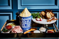 an assortment of meats and vegetables on a serving tray in front of blue doors