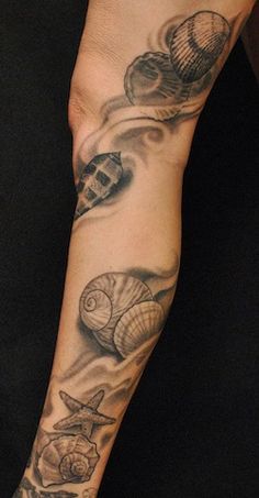 a person with a tattoo on their arm holding a cell phone and seashells