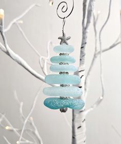 a glass ornament hanging from a tree in front of a white christmas tree