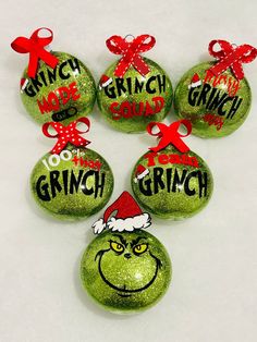 six grinch christmas ornaments with red bows and green baubles on white background