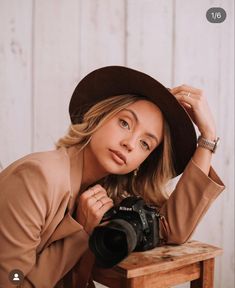 a woman with a hat is holding a camera