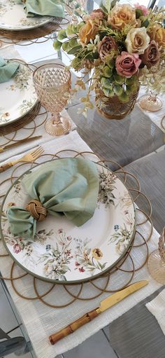 a table set with plates, napkins and flowers