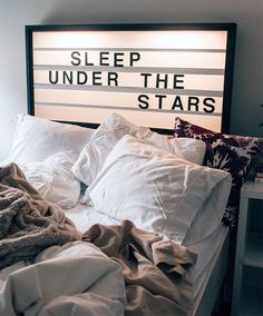 an unmade bed with white sheets and blankets on it, under the stars sign