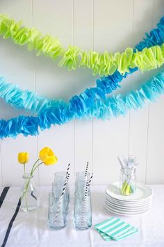 colorful streamers are hanging from the ceiling above a table with plates and cups on it